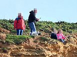 Shocking moment man makes two young children pose for a photo on top of 150ft unstable cliffs