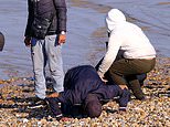 Jubilant migrant celebrates crossing the Channel by punching the air and kissing the beach