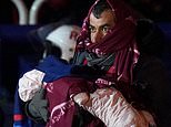 Migrant carrying baby wrapped in a blanket is brought ashore in Dover